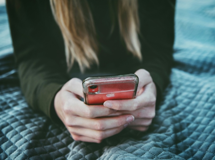 Girl with focus on her hands holding her phone and scrolling